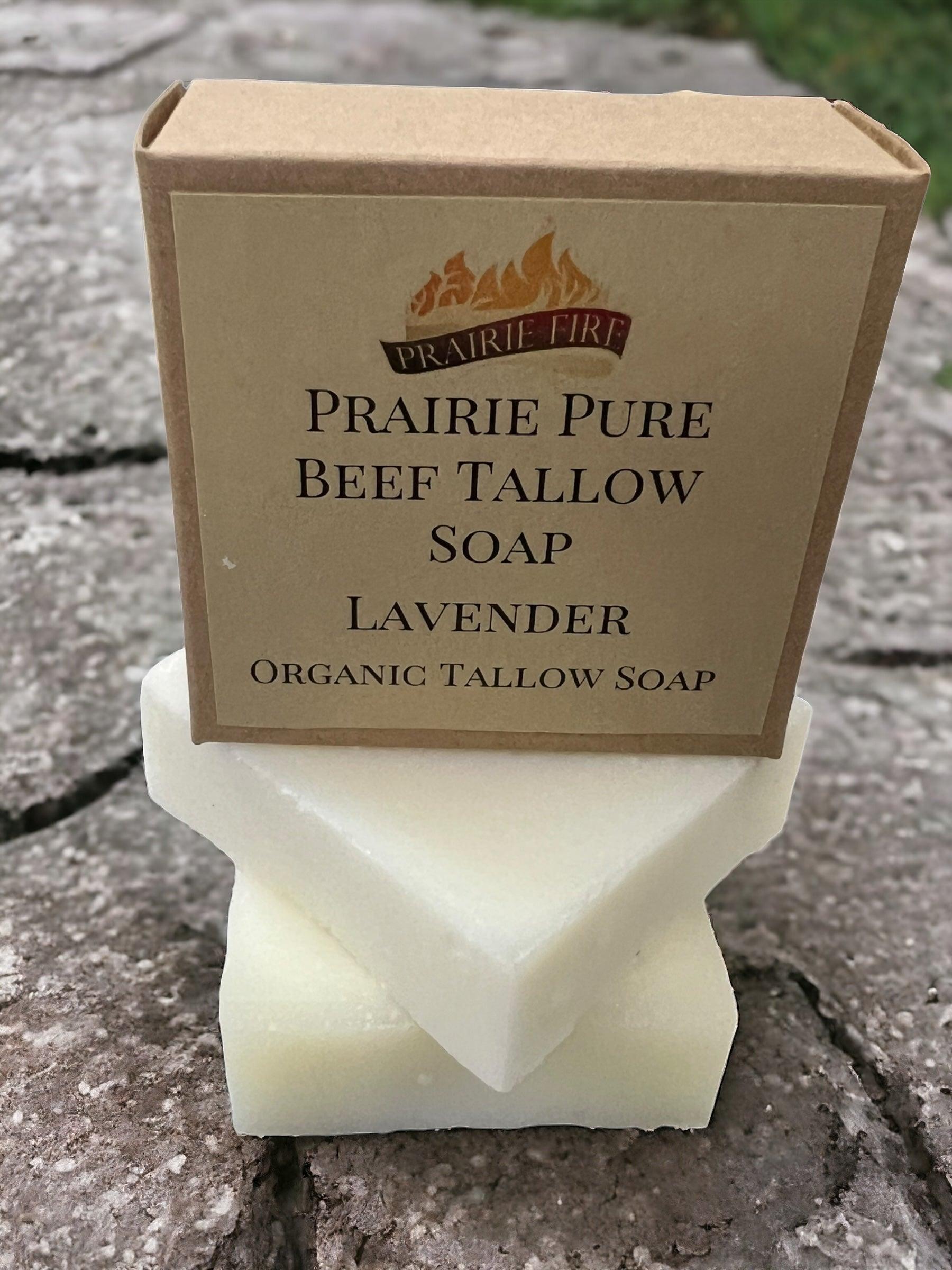 A Prairie Fire Tallow Pure Beef Tallow Soap Bar (3 Pack), Grass Fed and Finished, rests on two white bars outdoors. The brown packaging with clear labeling and a flame logo highlights its natural, organic ingredients for face, body, and hair.