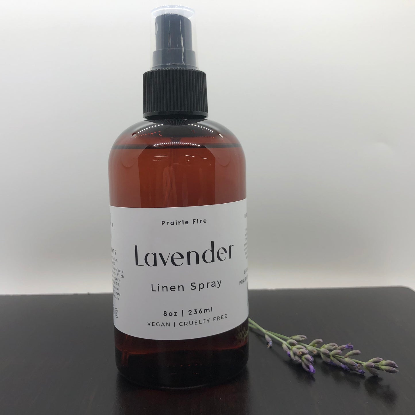 Lavender Linen Spray by Prairie Fire Tallow, Candles, and Lavender in an 8oz spray bottle with lavender flowers in the background.