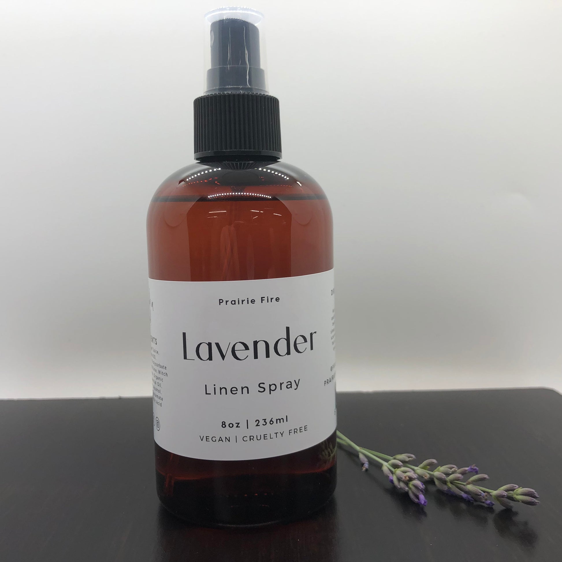 Lavender Linen Spray by Prairie Fire Tallow, Candles, and Lavender in an 8oz spray bottle with lavender flowers in the background.