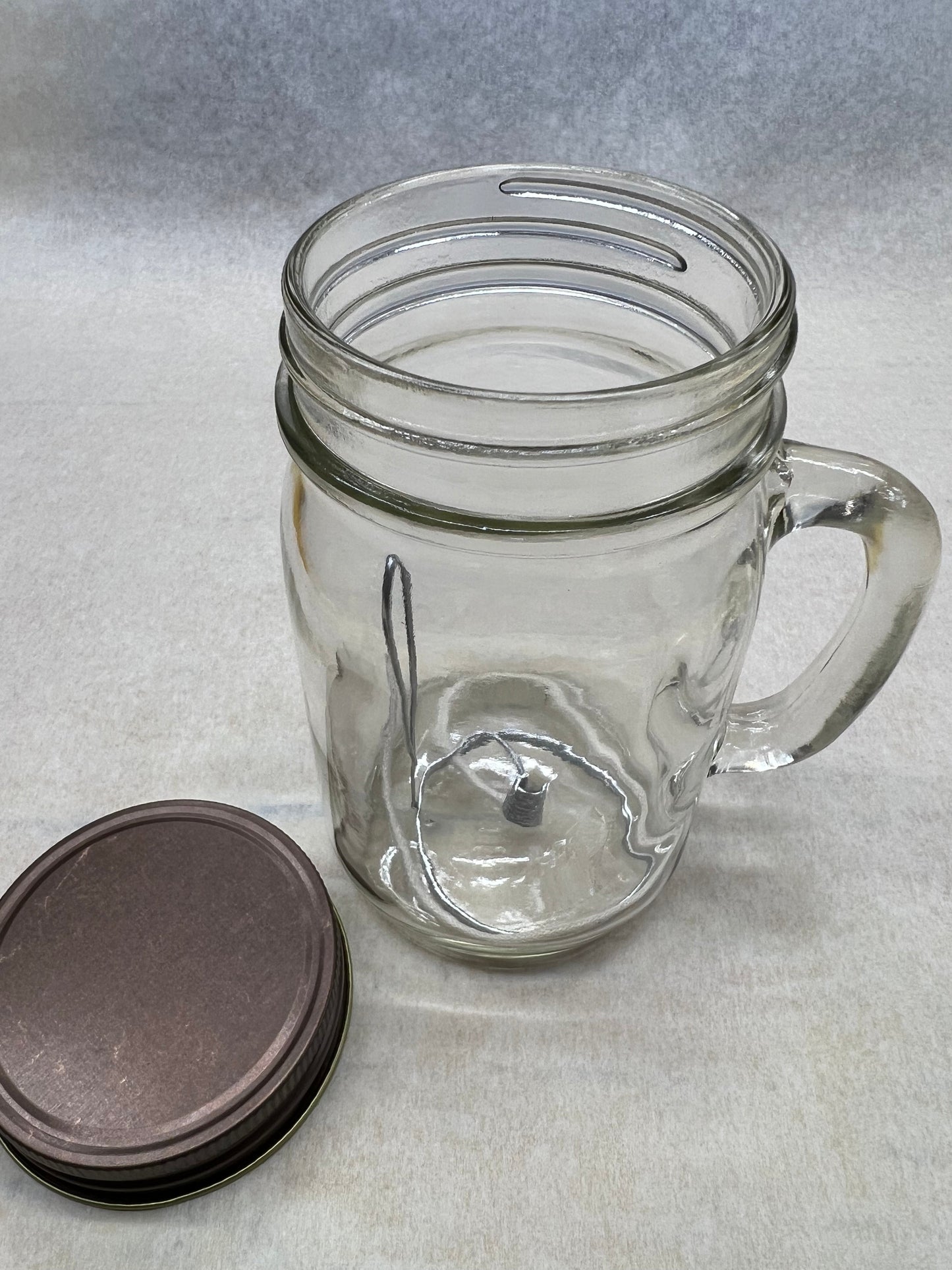 Olive oil candle lamp in a handle mason jar, used as an emergency backup light during power outages by Prairie Fire Tallow.