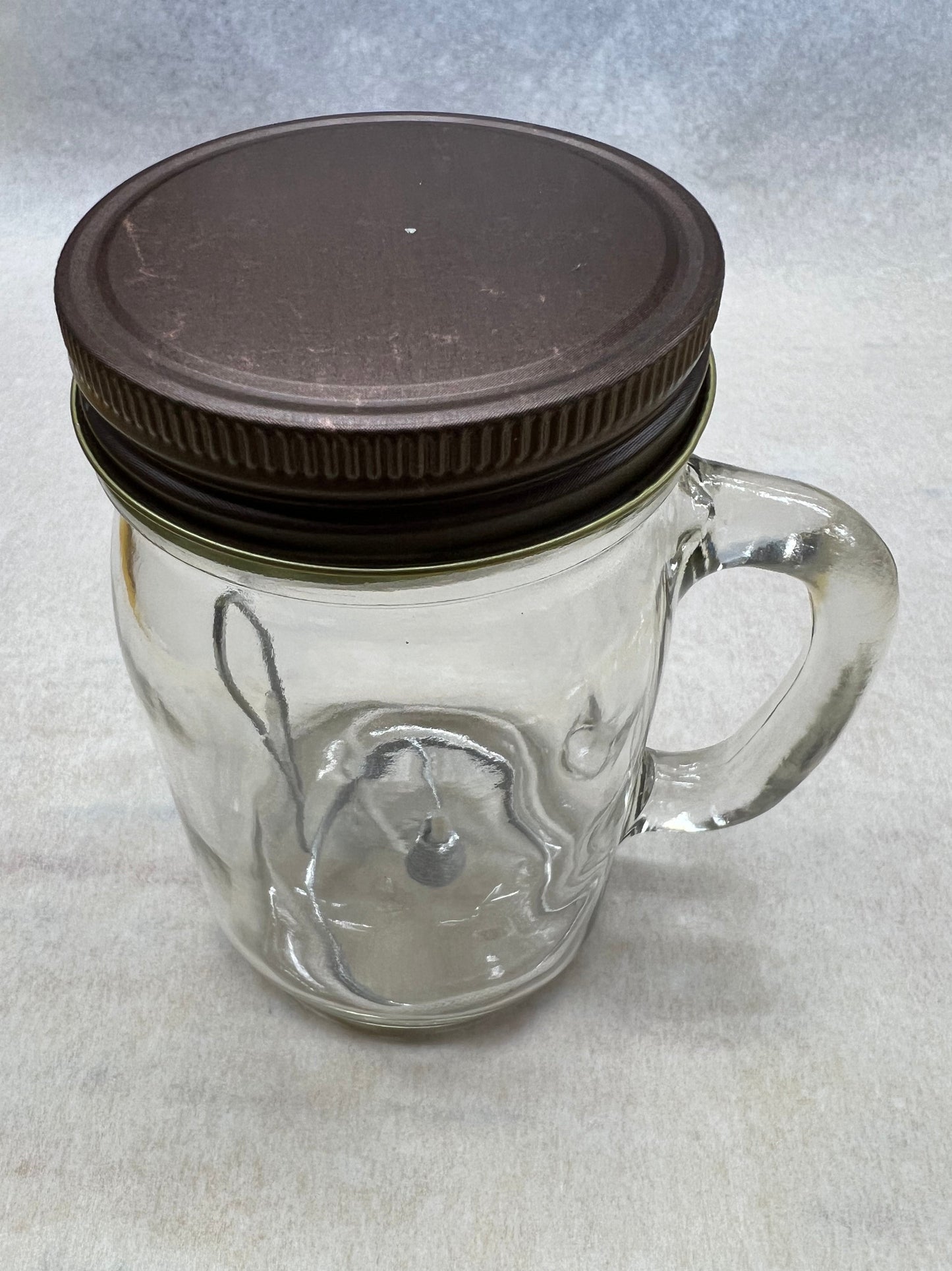 Olive oil candle lamp in a handle mason jar, used as an emergency backup light during power outages, by Prairie Fire Tallow.