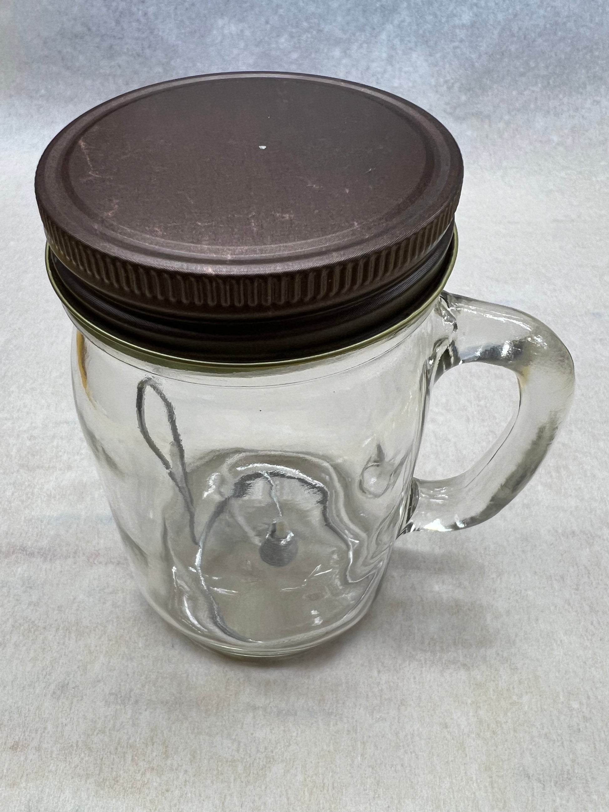 Olive oil candle lamp in a handle mason jar, used as an emergency backup light during power outages, by Prairie Fire Tallow.