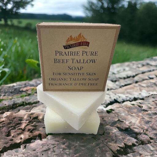 A pack of Pure Beef Tallow Soap Bars from Prairie Fire Tallow, Candles, and Lavender sits on stone amidst greenery. Made in the USA from grass-fed tallow, this natural, organic soap gently cleanses and hydrates face, body, and hair.