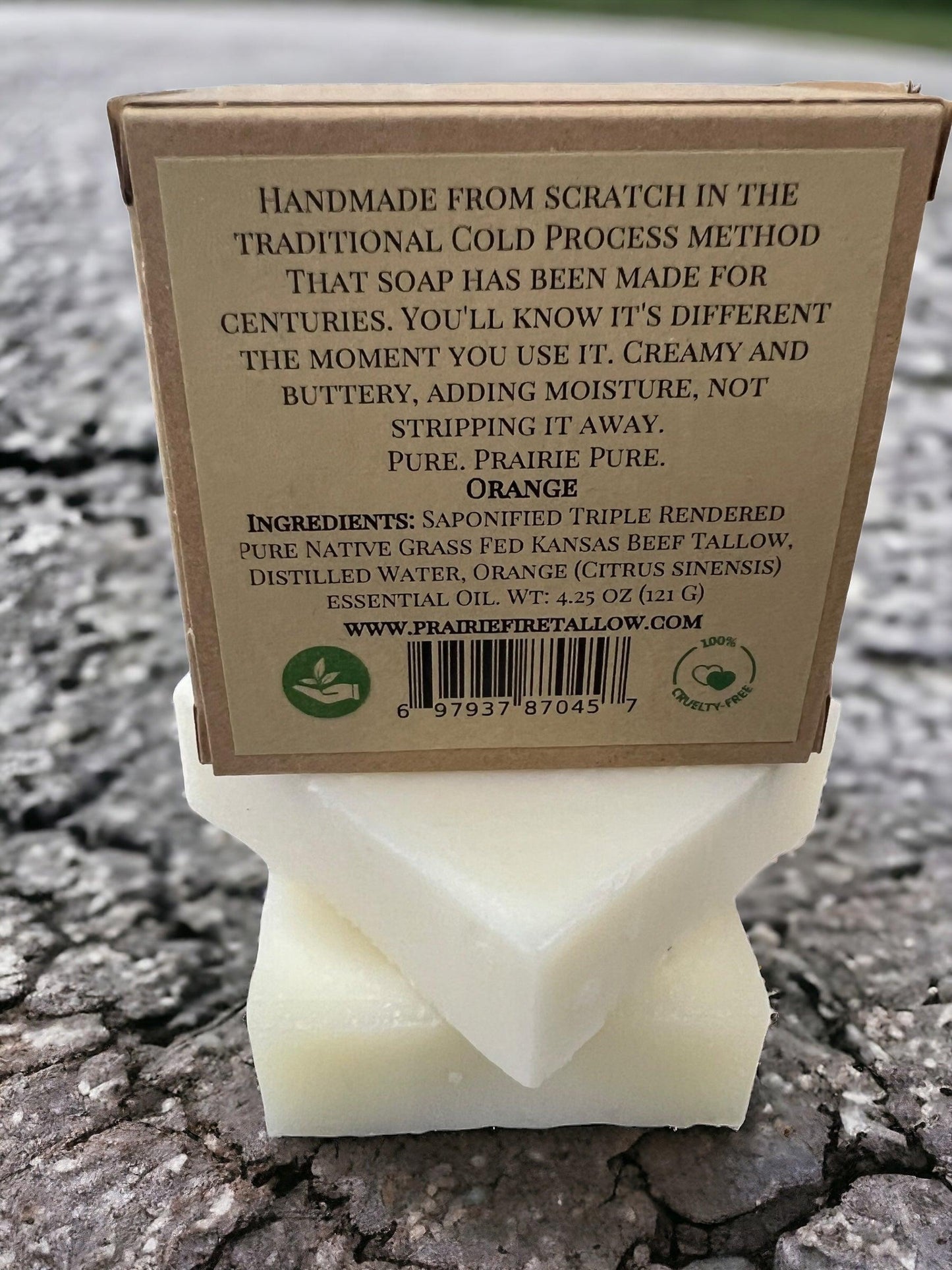 A Pure Beef Tallow Soap Bar 3-pack by Prairie Fire Tallow, Candles, and Lavender sits on cracked pavement. Grass fed and finished, it’s handmade in the USA with natural and organic ingredients for face, body, and hair.