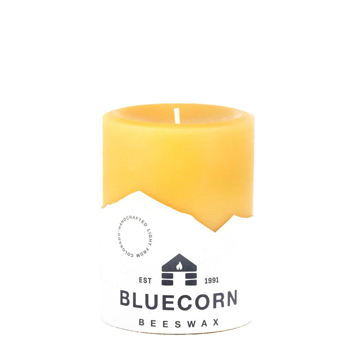 Set of three Bluecorn Candles pure beeswax pillar candles in natural yellow with unburned wicks on a wooden surface.