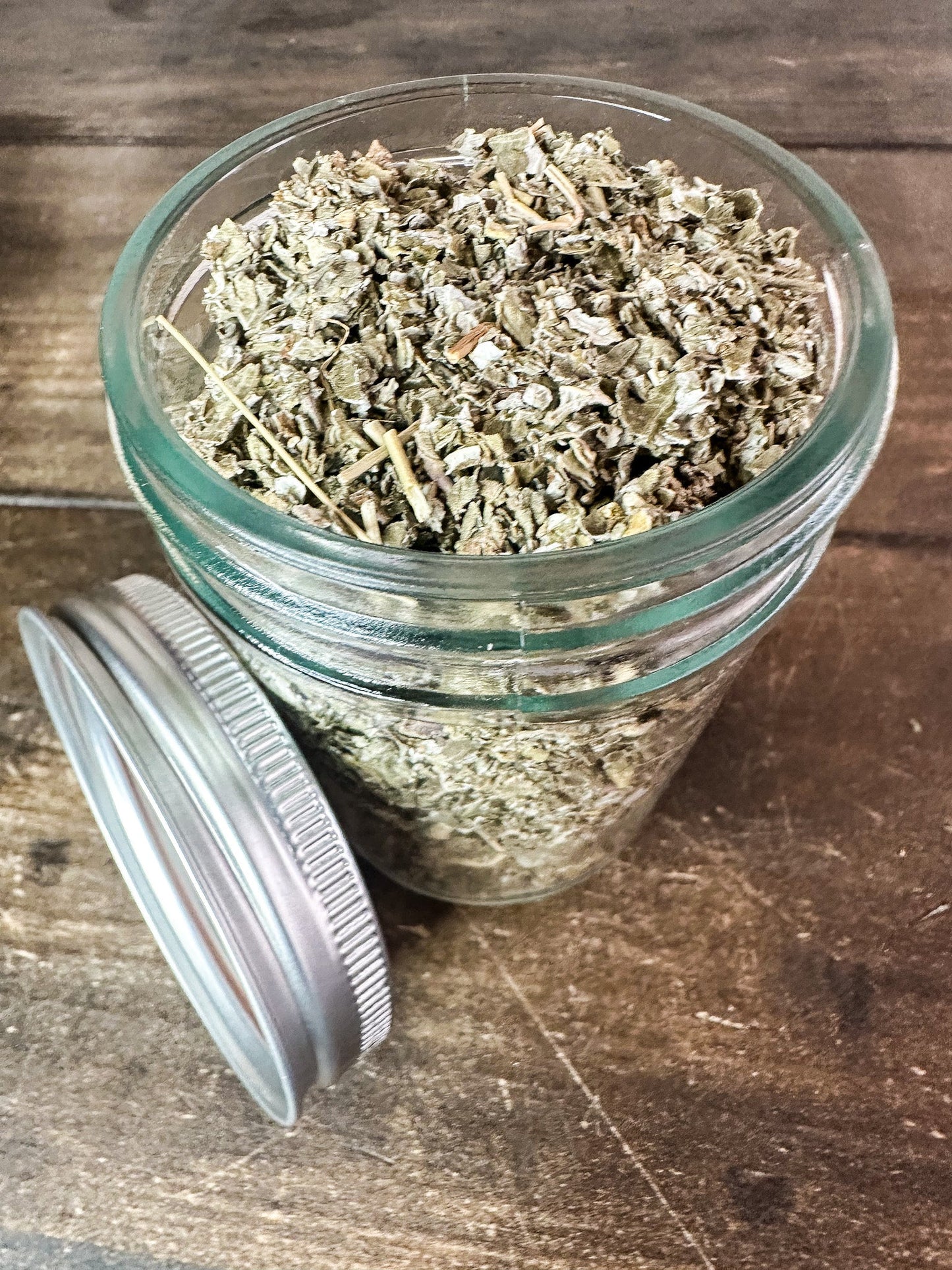 Small jar of dried herbs from HerbalRoseApothecary, featuring raspberry herbs in a clear glass herb jar.