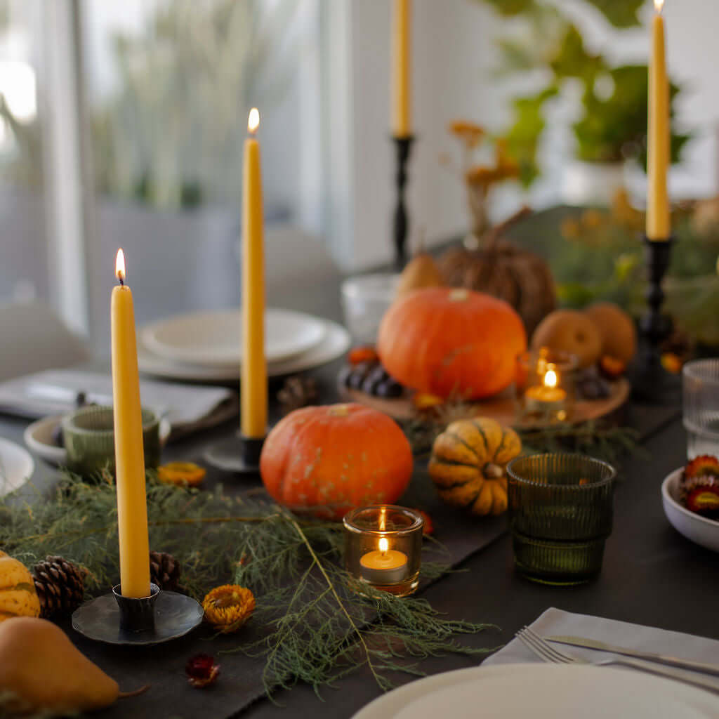Bluecorn Candles hand-dipped beeswax taper candles and tea lights on a fall dinner table, showcasing natural beeswax finish.