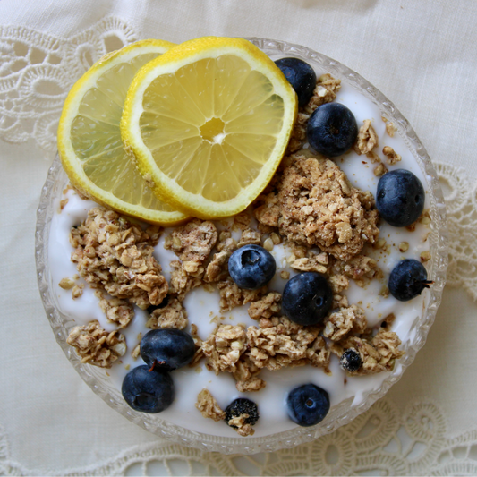 Rooted Living Blueberry Lemon Granola in a bowl with blueberries and lemon slices, showing the crunchy texture and fresh ingredients.