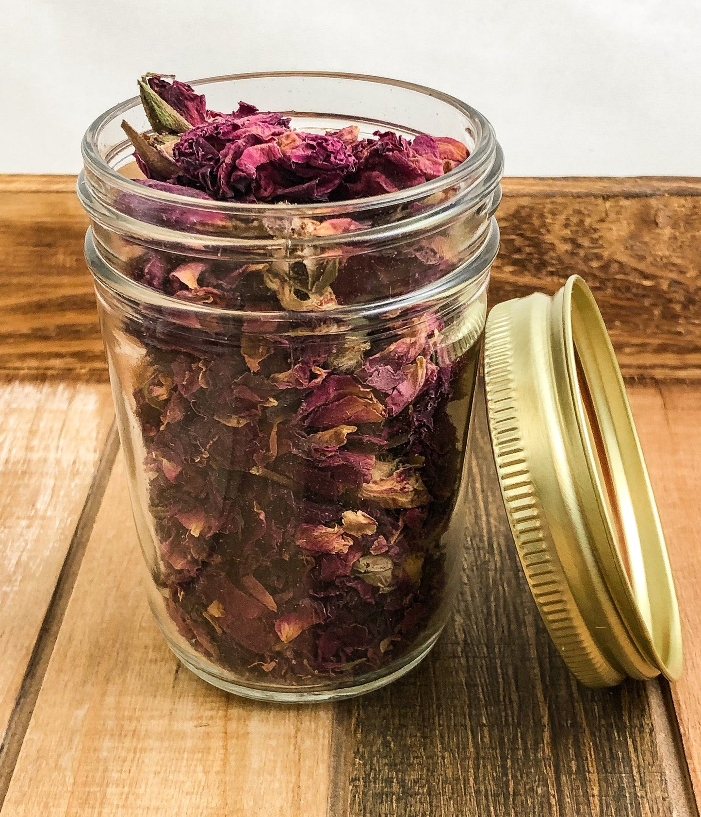 Small herbal jars with wooden lids containing dried herbs, featuring a white background and the HerbalRoseApothecary brand.