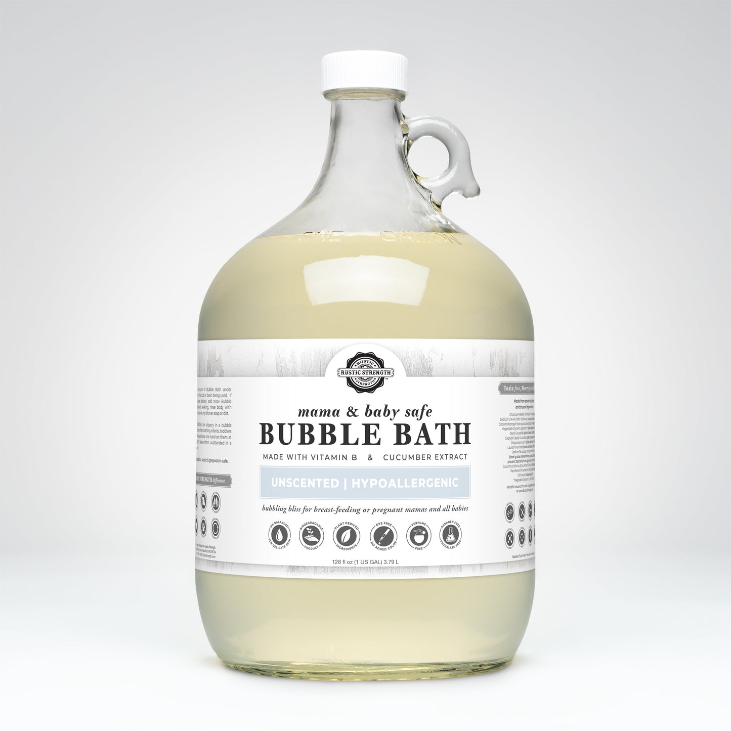 A large, clear jug with a handle contains Rustic Strength Bubble Bath | Mama + Baby Safe. The white label states its hypoallergenic, unscented, made with vitamin B & cucumber extract, and lists baby-safe ingredients.