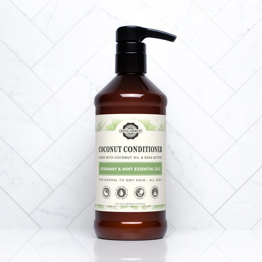 Rustic Strength Coconut Conditioner with rosemary and mint in a 16 oz bottle, showing the conditioner's creamy texture.