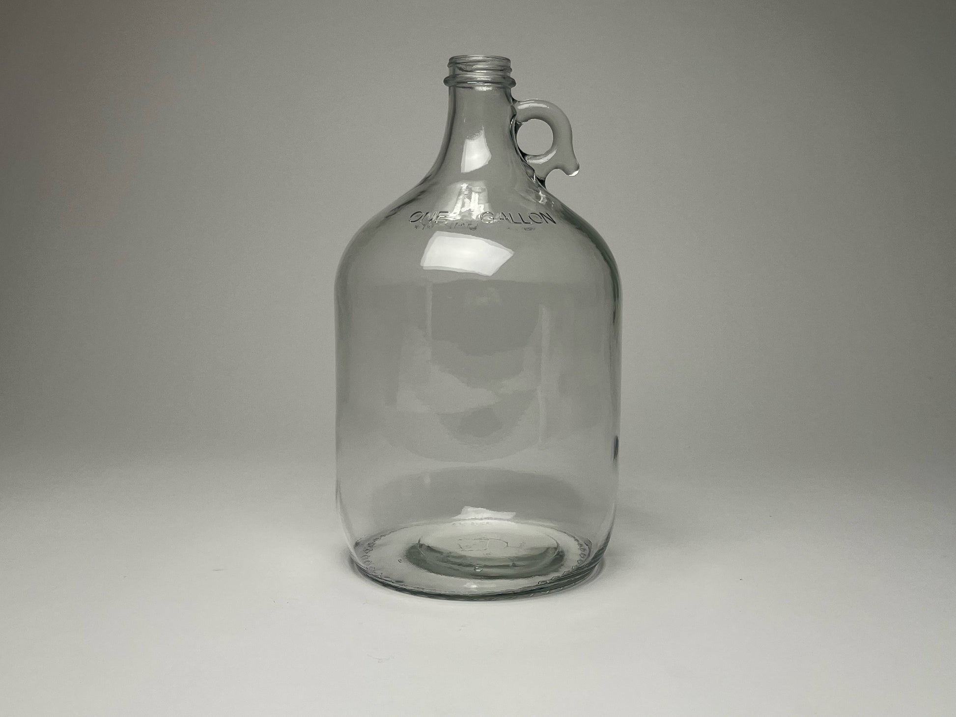 The Rustic Strength 1 Gallon Glass Jug with Cap, featuring a handle near the neck, is shown against a plain light gray background. This popular item is available in limited stock.