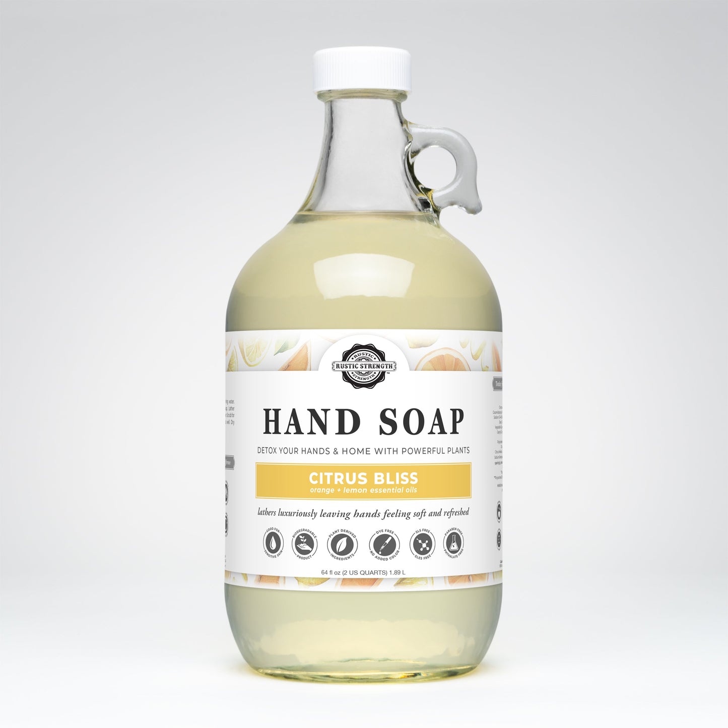 A clear glass bottle with a handle contains Rustic Strength’s Hand Soap | Citrus Bliss, a gentle liquid hand soap featuring citrus essential oils. The label displays citrus fruits, the brand logo, and usage details.
