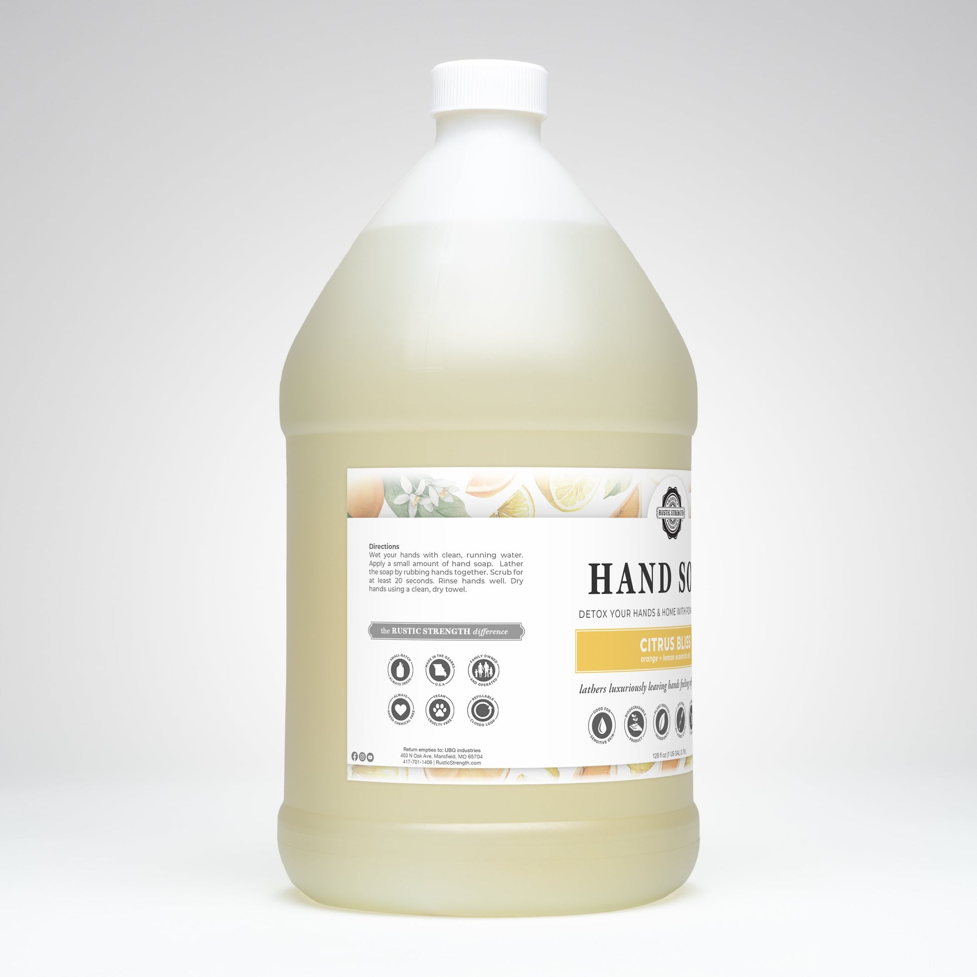 A large, transparent plastic jug with a white cap contains Rustic Strength Hand Soap | Citrus Bliss. The label displays the product name, instructions, and icons. The background is plain white.
