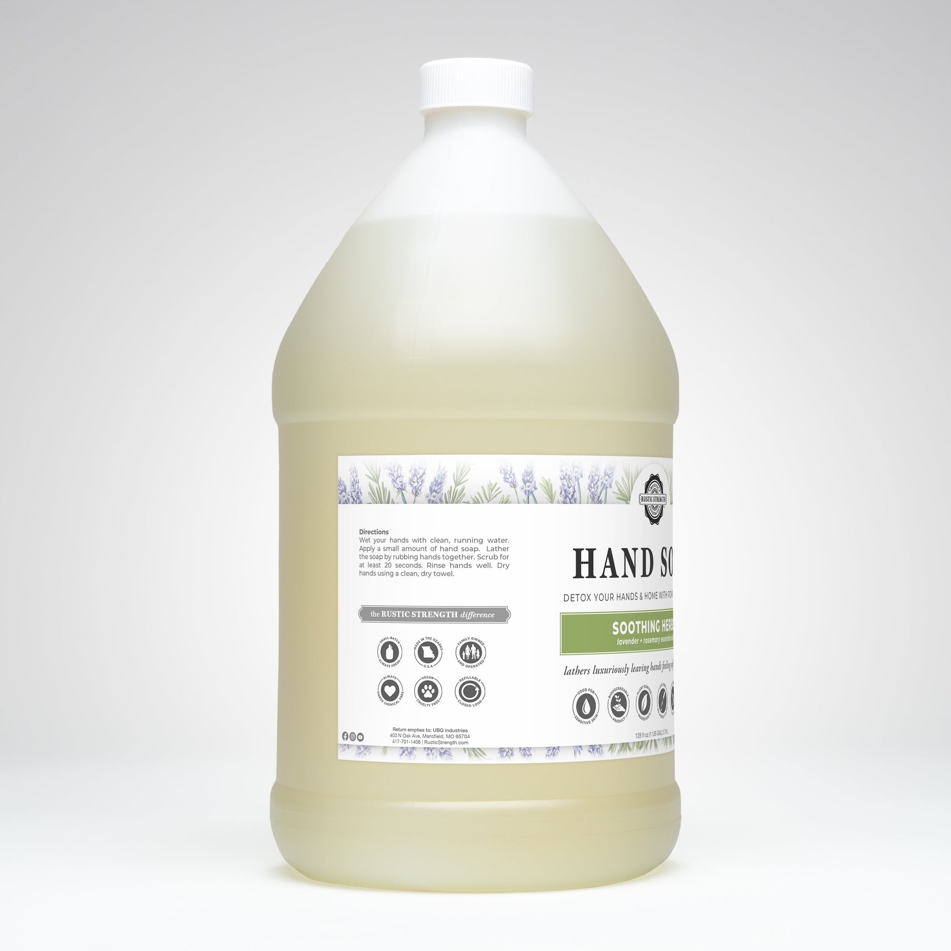 A large, clear plastic jug of pale yellow Rustic Strength Hand Soap | Soothing Herbs features lavender illustrations and highlights its biodegradable formula, directions, and ingredients on a white label.