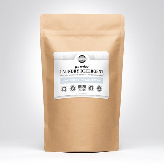 A brown paper bag of Rustic Strength Powder Laundry Detergent with a white label displays features like unscented, hypoallergenic, and 32 loads, set against a plain gray background.