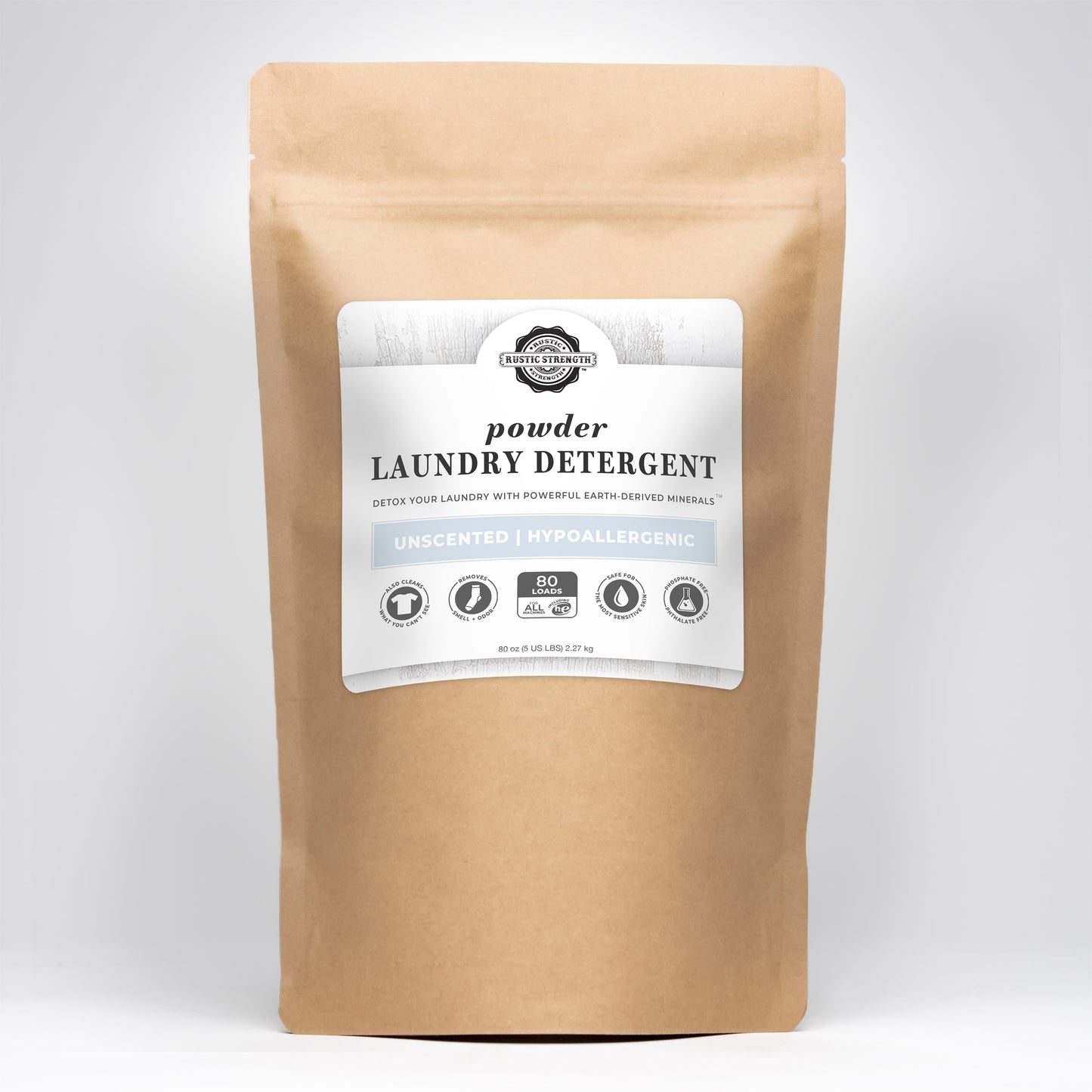 A brown paper pouch with a white label reading Rustic Strength Powder Laundry Detergent, Unscented, Hypoallergenic, 90 loads—this sensitive skin safe detergent features earth-derived minerals and a non-toxic formula.