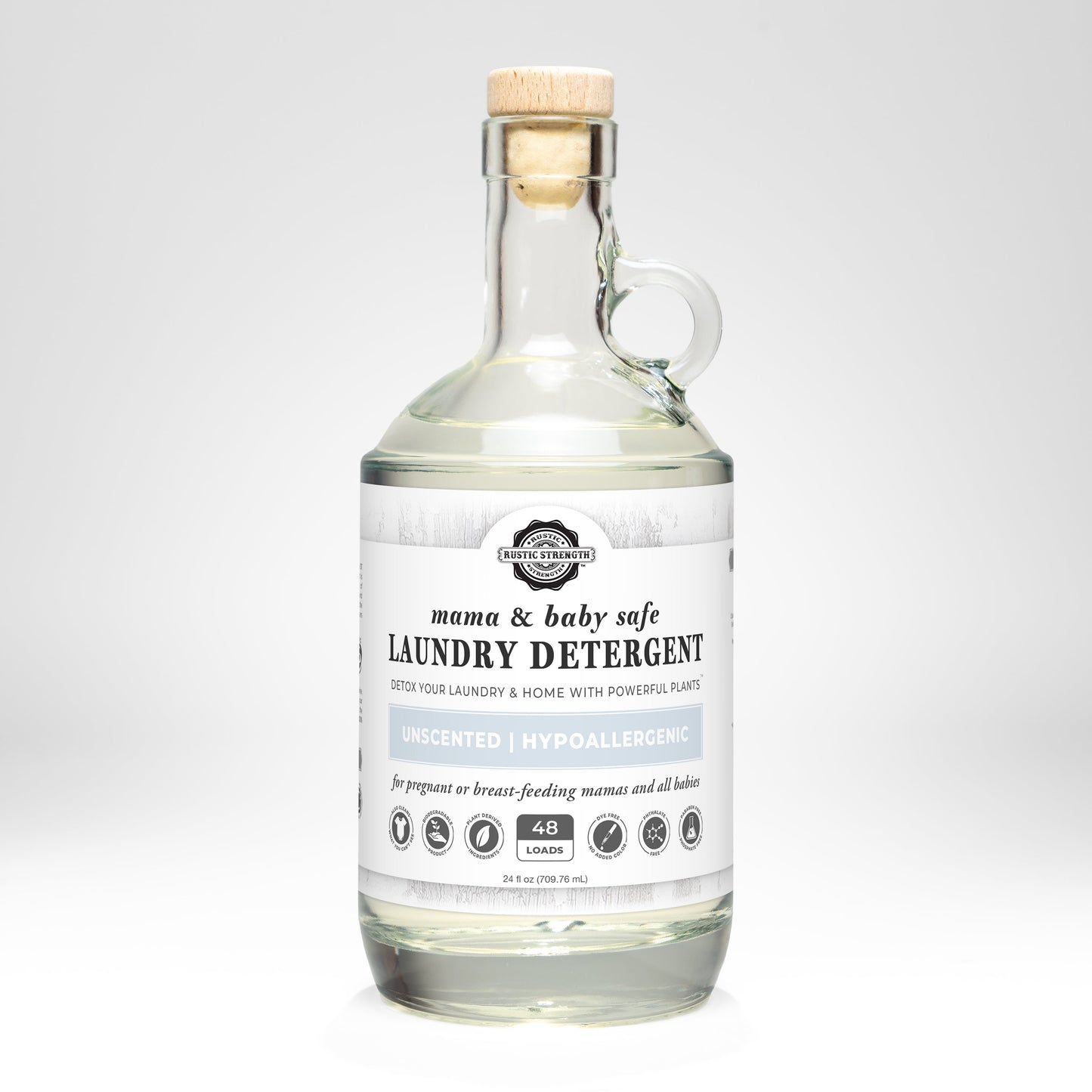 A clear glass bottle with handle contains Rustic Strength Laundry Detergent | Mama + Baby Safe for sensitive skin, unscented, 48 loads, shown against a plain white background.