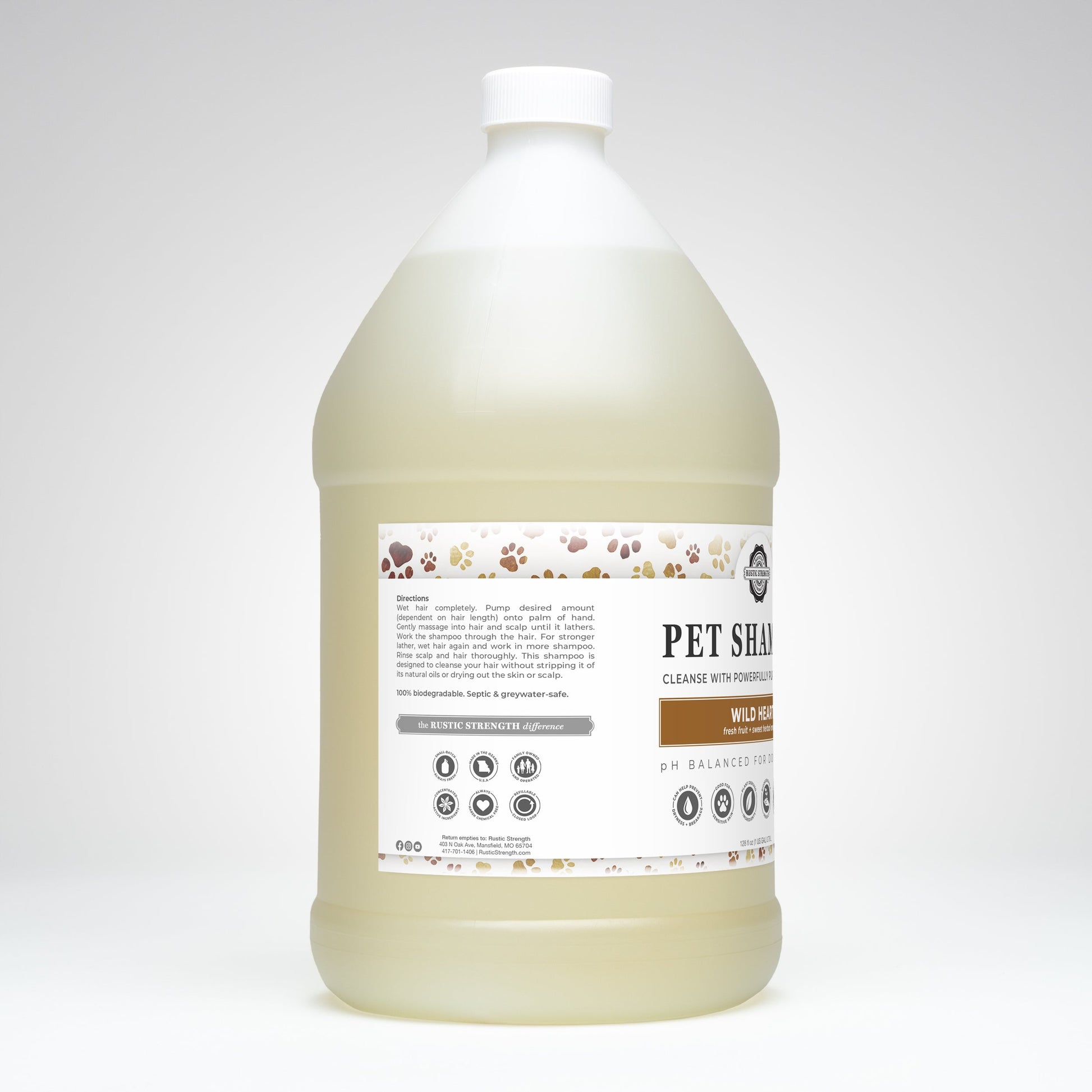A large, clear plastic gallon jug with a white cap contains light yellow Pet Shampoo by Rustic Strength—Soothing & Deodorizing, plant-based and non-toxic. The label features paw prints and product info, branded as Wild Heart.