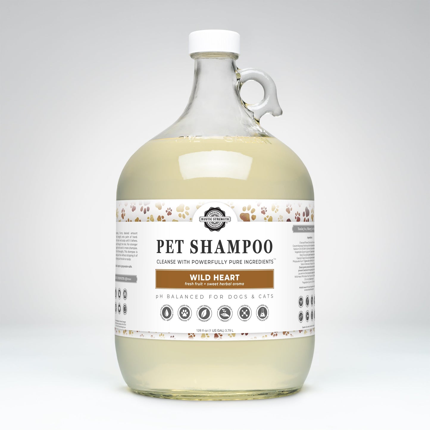 A large clear jug of Rustic Strength Pet Shampoo | Soothing & Deodorizing | Wild Heart has a paw print design, white cap, and handle. The label notes plant-based ingredients, is pH balanced for dogs and cats; the non-toxic liquid inside is light yellow.
