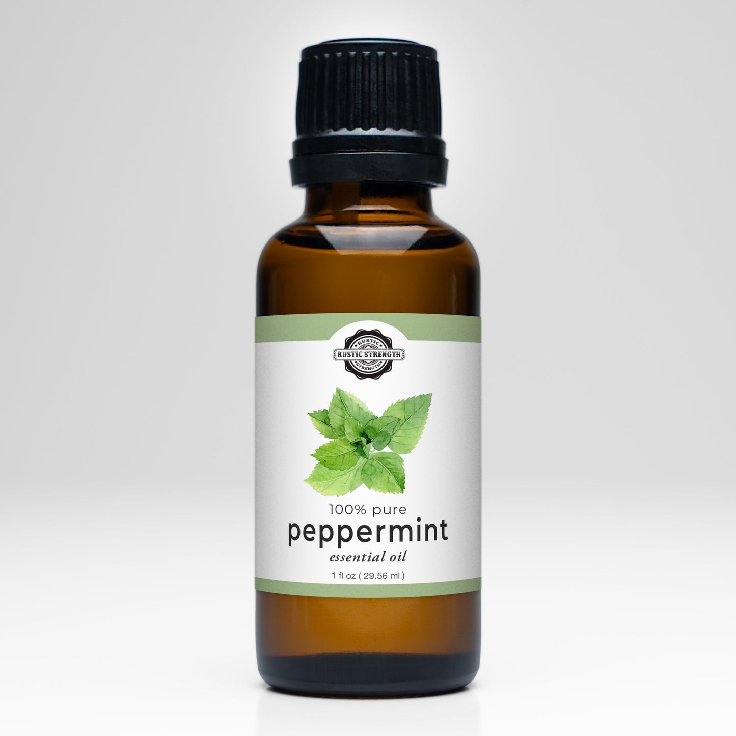 A brown glass bottle with a black cap labeled Rustic Strength Peppermint Essential Oil. The 1 fl oz (29.56 ml) label shows peppermint leaves and states its 100% pure. Ideal for aromatherapy, set against a plain white background.