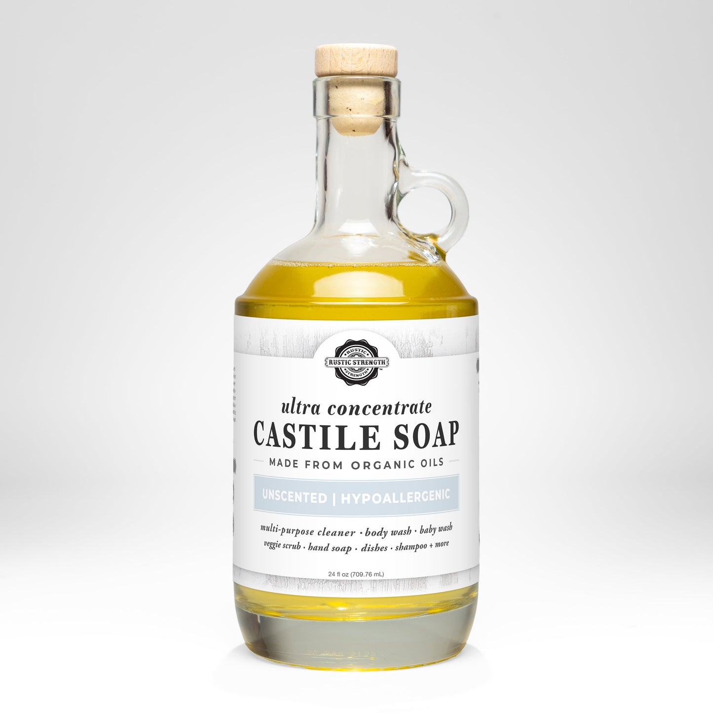 A clear glass bottle with a cork stopper contains Rustic Strength’s Castile Soap - Ultra Concentrate | Unscented, a hypoallergenic multi-purpose cleaner made from organic oils; the label lists various uses and notes it is unscented.