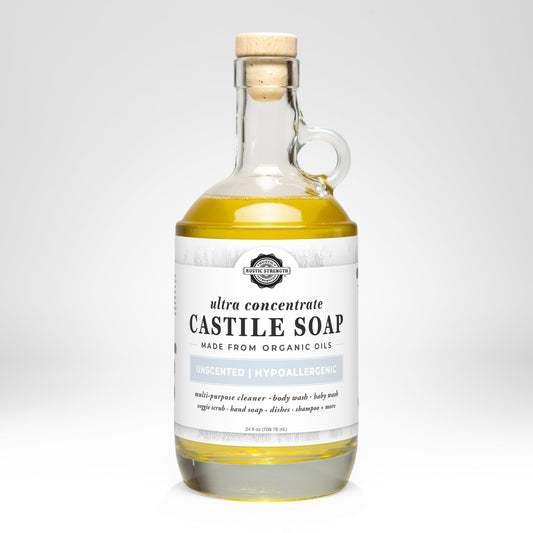 A clear glass bottle with a cork stopper contains Rustic Strength’s Castile Soap - Ultra Concentrate | Unscented, a hypoallergenic multi-purpose cleaner made from organic oils; the label lists various uses and notes it is unscented.