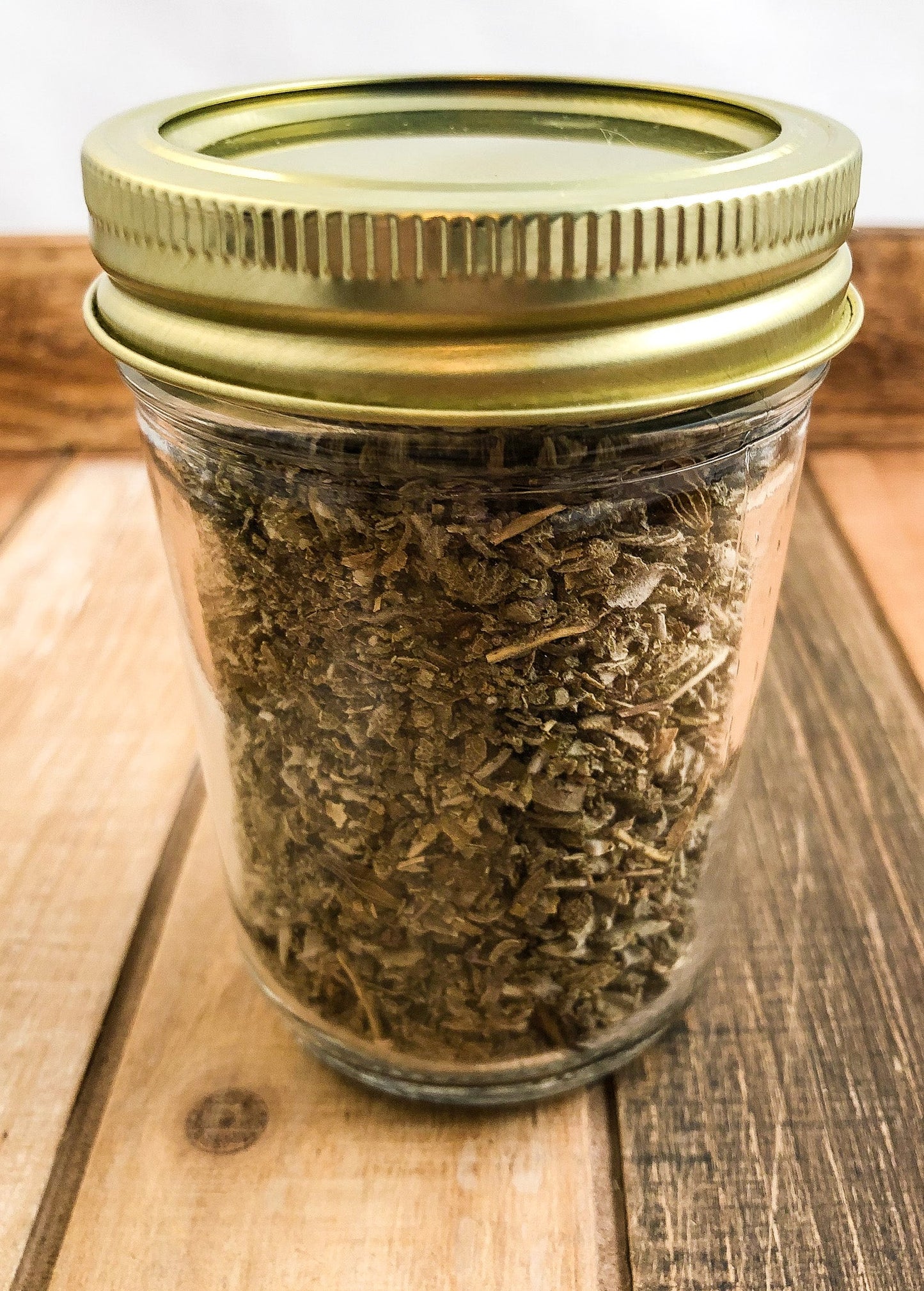 Small jar of dried sage herbs from HerbalRoseApothecary, featuring a white and wood-colored herbal jar with sage inside