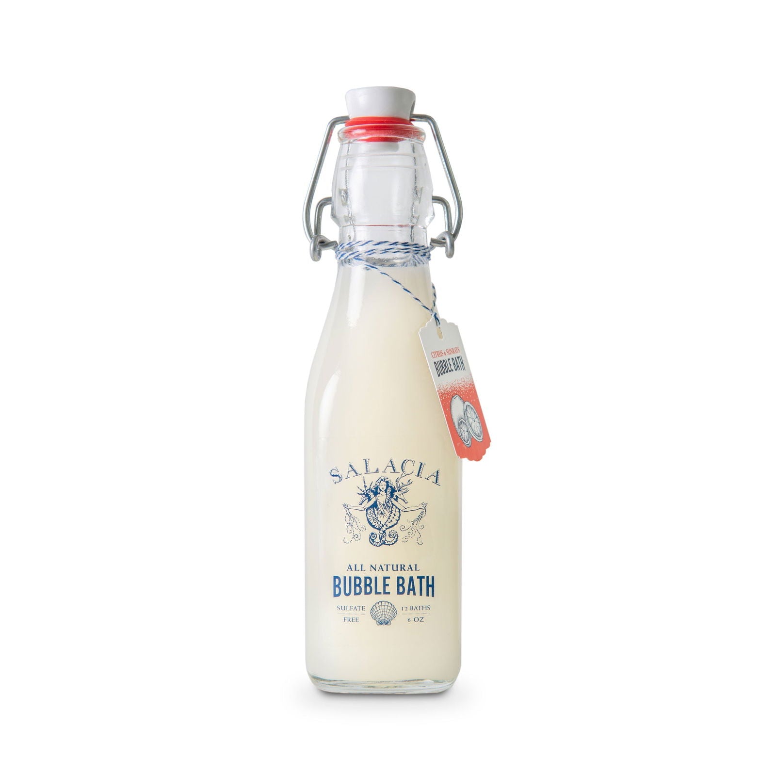A clear glass bottle with a swing-top lid contains a creamy, moisturizing liquid labeled Salacia Salts Citrus & Sunrays Bubble Bath. A tag is tied around the neck of the bottle with blue and white string.