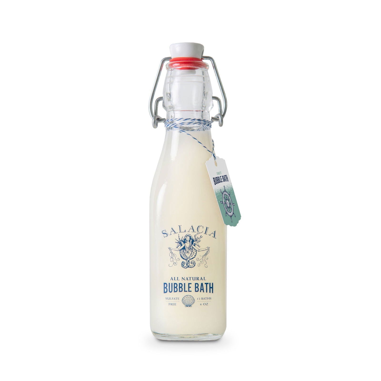 Salacia Salts' Drift Bubble Bath comes in a clear glass bottle with a swing-top lid. The white, coconut oil-infused formula shows through, finished with blue label text and a string-tied tag around the neck.