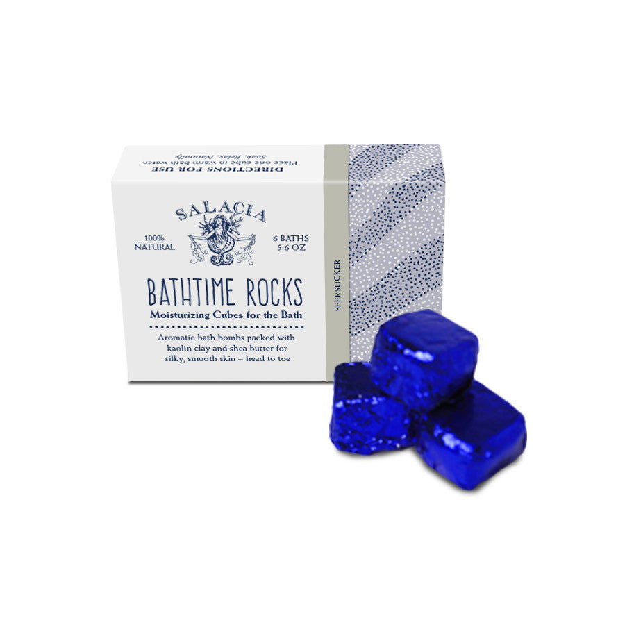 A box labeled Seersucker BathTime Rocks (Set of 6) by Salacia Salts sits next to three shiny blue cube-shaped bath bombs. The box describes them as aromatic, moisturizing cubes for the bath and includes product details.
