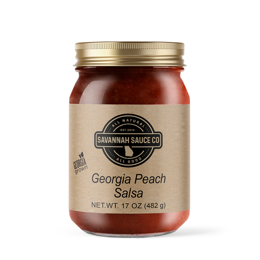 A 17 oz (482 g) glass jar of SavannahSauceCompany Georgia Peach Salsa, featuring "All Natural" and "Georgia Grown" on a beige label, made with diced tomatoes and jalapeno peppers, topped with a gold lid.