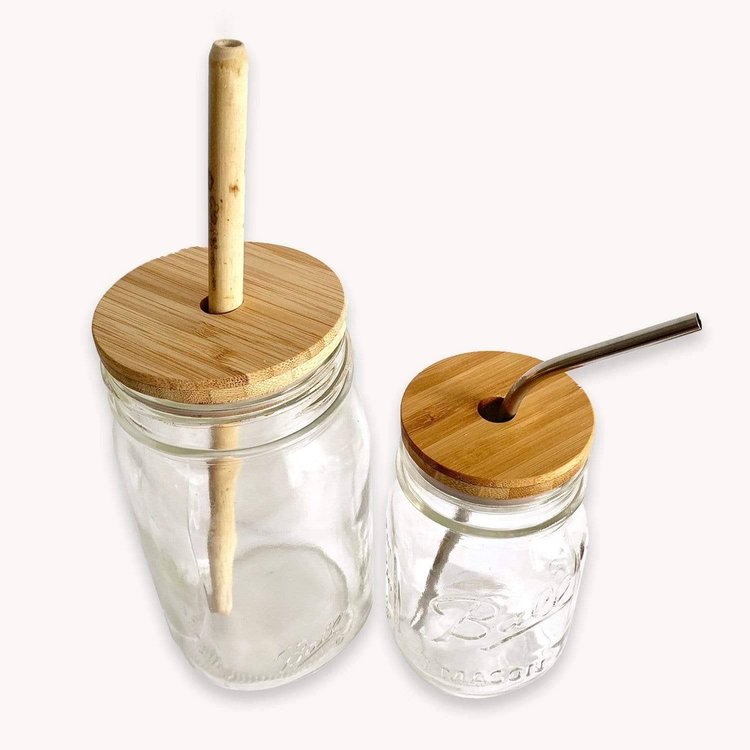 Two clear mason jars of different sizes with ZeroWasteStore.com Bamboo Mason Jar Lids and reusable straws—one bamboo, one metal—are shown on a white background. Each eco-friendly lid has a hole for a straw.