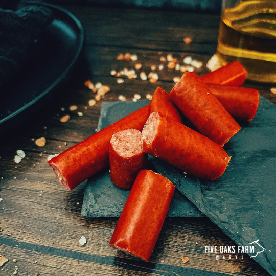 Five Oaks Farm Wagyu Wagyu snacksticks in a box, showcasing thin, seasoned beef snacksticks with a rustic presentation.