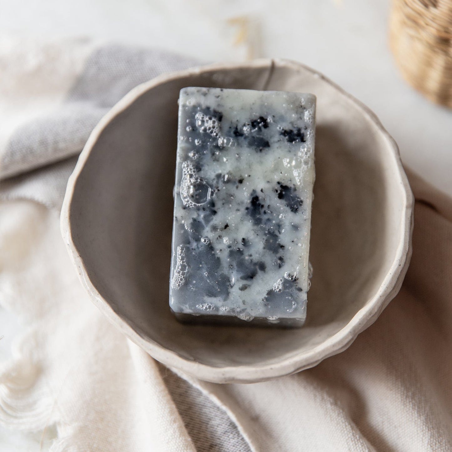 A 4oz, all-natural vegan soap bar from ZeroWasteStore.com, available in 6 scents, sits in a ceramic dish on neutral fabric—plastic-free and perfect for face and body.