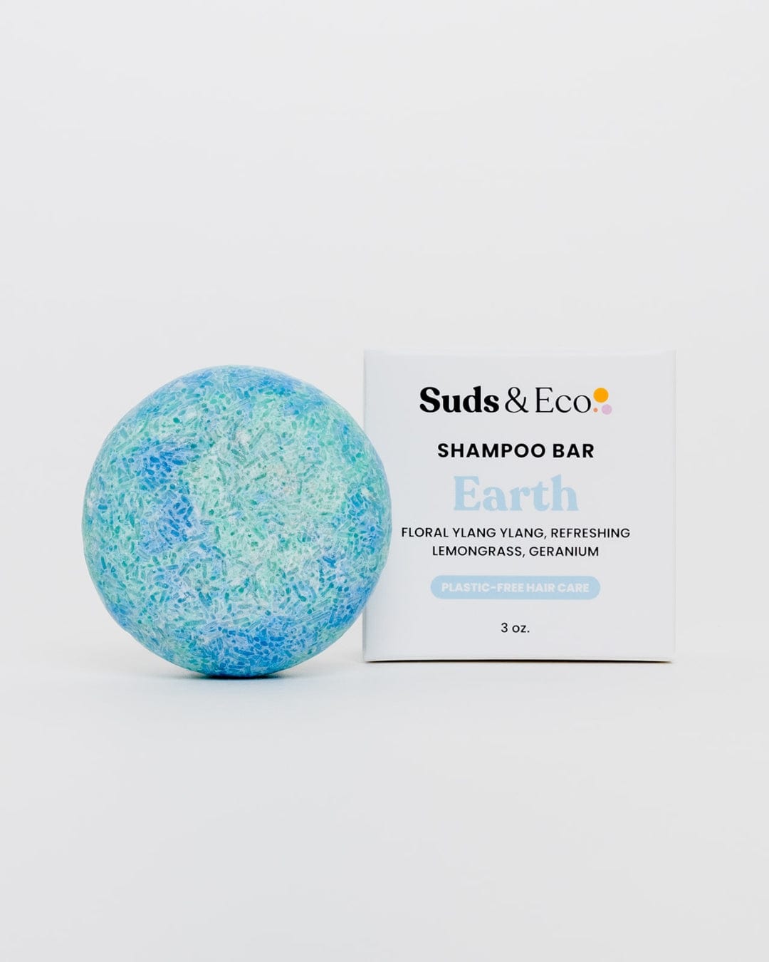 A blue and green round Shampoo Bar from ZeroWasteStore.com sits beside a white box, showcasing its floral scent, zero waste formula, and plastic-free packaging on a plain white background.
