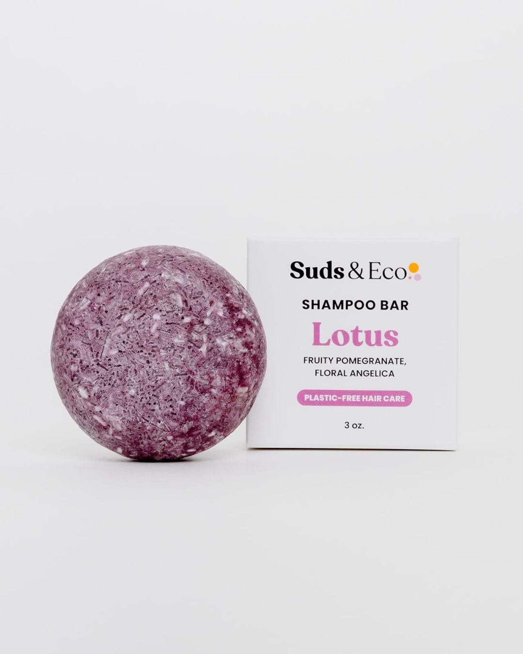 A round, purple ZeroWasteStore.com Shampoo Bar sits by its box labeled Lotus. Scented with Fruity Pomegranate & Floral Angelica. Vegan and zero waste for plastic-free hair care. 3 oz., displayed on a plain white background.