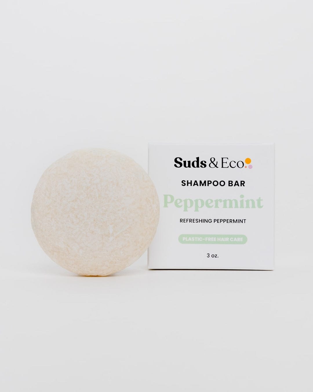 A round, off-white Shampoo Bar from ZeroWasteStore.com sits beside its box labeled "Peppermint" and "Zero Waste Shampoo Hair Care, 3 oz." on a plain white background.