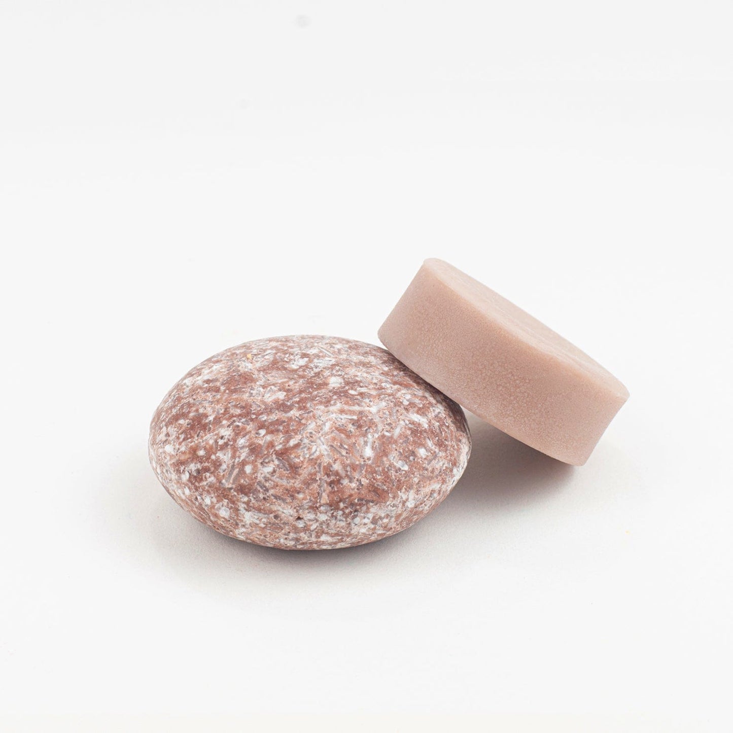 The Shampoo & Conditioner Bar Duo from ZeroWasteStore.com features two round bars—one light brown and smooth, the other speckled and textured—ideal for an eco-friendly, zero waste hair care routine.