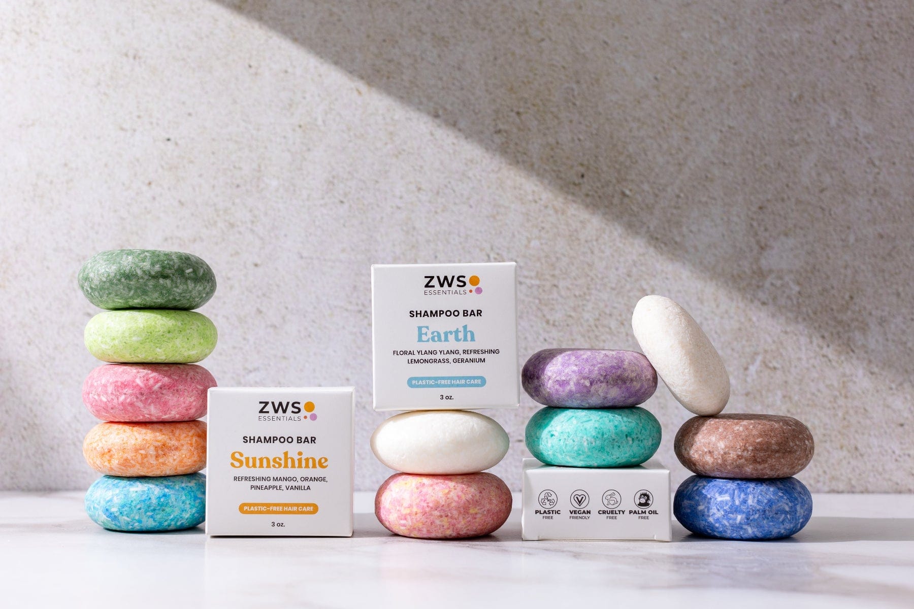 Colorful Shampoo Bars from ZeroWasteStore.com are stacked by two white boxes labeled Sunshine and Earth. These zero waste bars offer an eco-friendly, vibrant upgrade for your hair care routine.