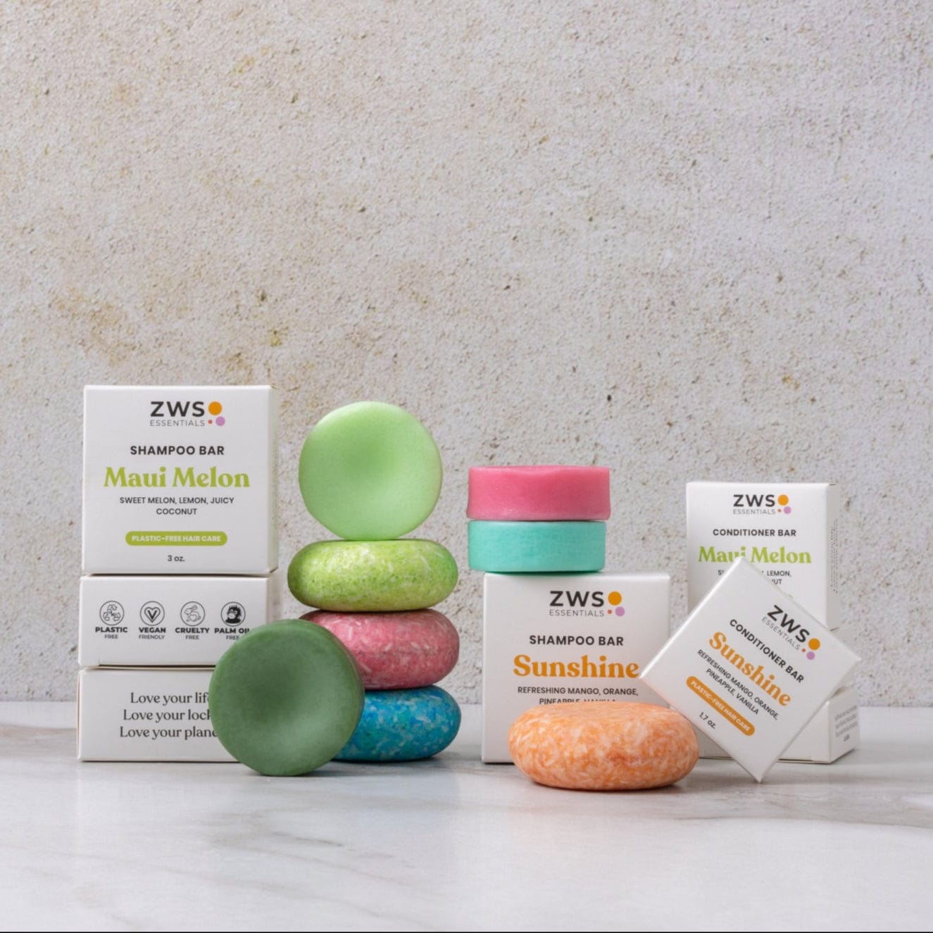 Five vibrant Shampoo & Conditioner Bar Duos from ZeroWasteStore.com are stacked before white ZWS Essentials boxes, highlighting a zero waste hair care option. The bars and boxes sit on a light surface against a plain background.