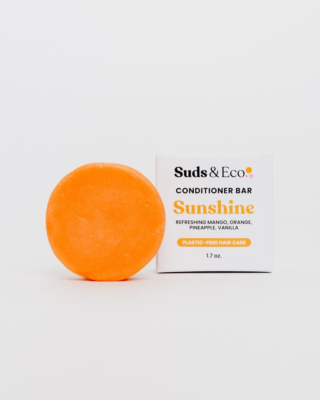 An orange, round sulfate-free Conditioner Bar from ZeroWasteStore.com sits beside its white box. It features a refreshing mango, orange, pineapple, and vanilla scent—perfect for zero waste, eco-friendly hair care.