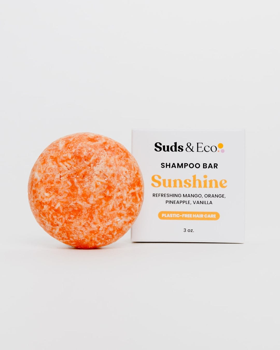 The round, orange Shampoo Bar from ZeroWasteStore.com sits beside its white box. With mango, orange, pineapple, and vanilla scents, it offers a vegan, zero waste solution for plastic-free hair care.