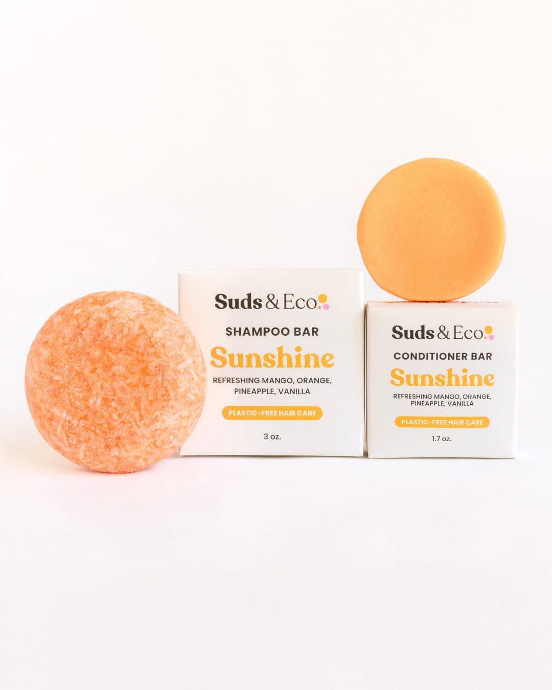 Two orange Shampoo & Conditioner Bar Duos from ZeroWasteStore.com sit beside their white “Sunshine” boxes, featuring mango, orange, pineapple, and vanilla scents—a zero waste option against a clean white background.