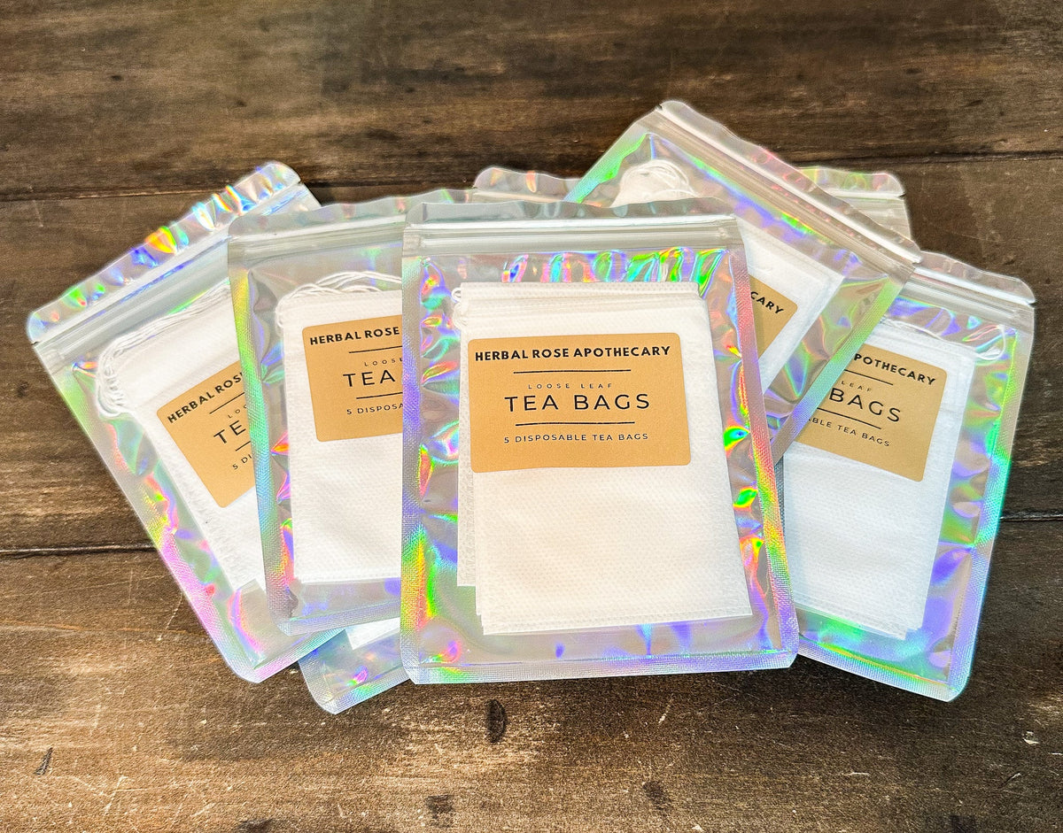 Set of five herbal tea bags from Herbal Rose Apothecary displayed on a wooden background. Organic tea bag set for brewing.