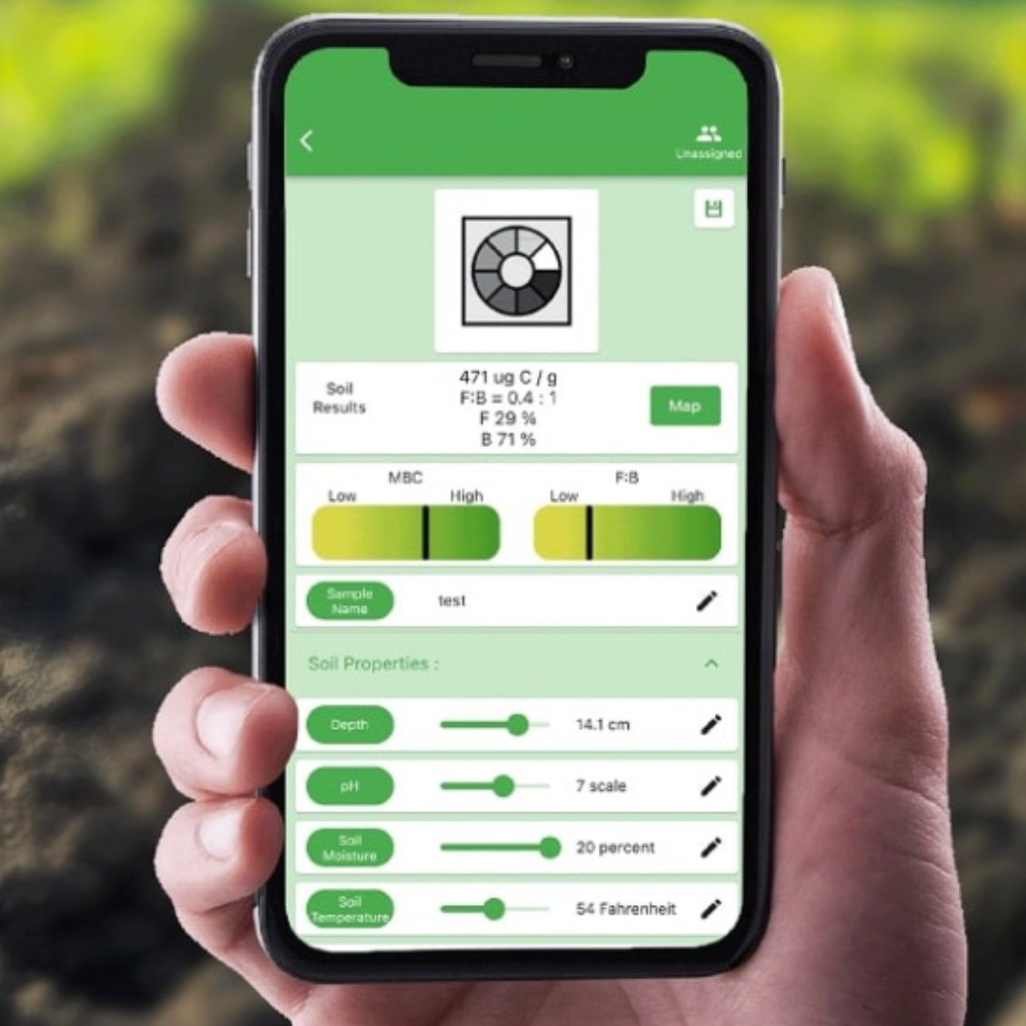 A hand holds a smartphone showing the microBIOMETER® Soil Testing Kit app by Teraganix Wholesale, featuring soil results charts, sample names, and adjustable sliders for depth, density, microbial biomass, and fungal to bacterial ratio. Ideal kit companion.