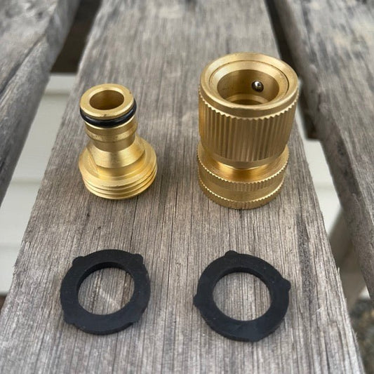 Two Garden Hose Brass Quick Connect Connectors by The Celtic Farm and two black rubber washers rest on a weathered wooden surface. The connectors ensure a leak-proof fit, with the washers below for added reliability.