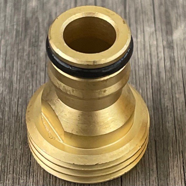 The Celtic Farm Garden Hose Brass Quick Connect Connector—a cylindrical fitting with a black O-ring and threaded end—lies on wood, ensuring a leak-proof garden hose connection.