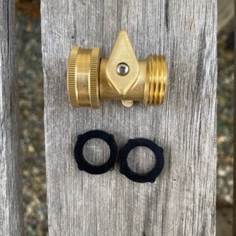 The Celtic Farm Garden Hose Brass Shutoff Valve features a lever and two black rubber washers for a leak-proof connection, shown resting on a weathered wooden surface.