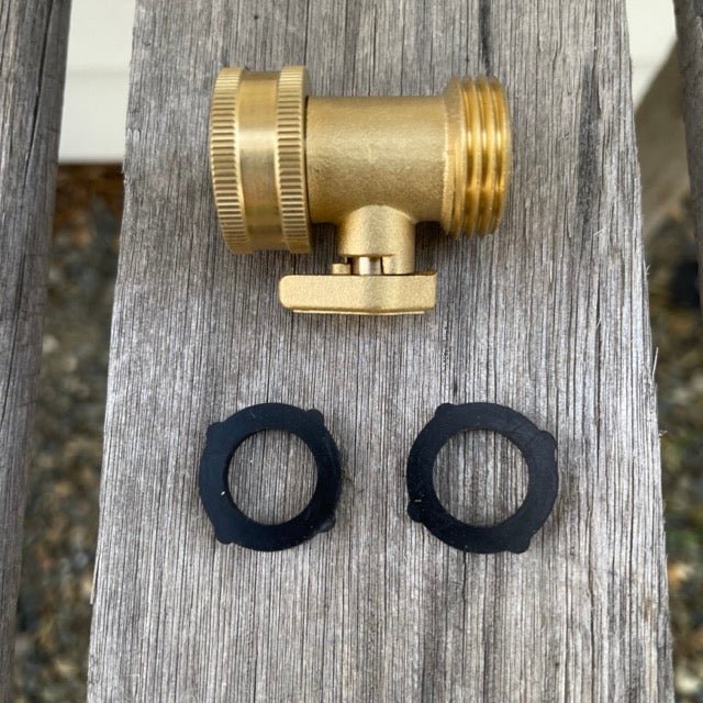 The Celtic Farm Garden Hose Brass Shutoff Valve with lever sits on a wooden surface, accompanied by two black plastic washers below for a leak-proof connection.